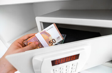 Man puts or takes euro banknotes from a safe.