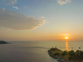 Fototapeta premium Aerial view of beautiful sky The sun reflects off the sea at Laem Phromthep Viewpoint at sunset..The tip of the cape juts out into the sea at Laem Phrom Thep Viewpoint.