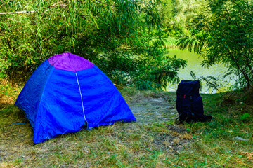 Blue tent and backpack in a forest on summer