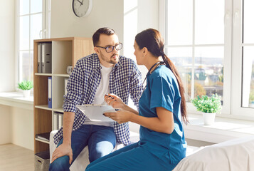 Portrait of a young man patient in medical doctor office listening to a friendly female nurse...