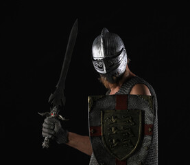 portrait of a male knight in chain mail with a sword and shield on a black background