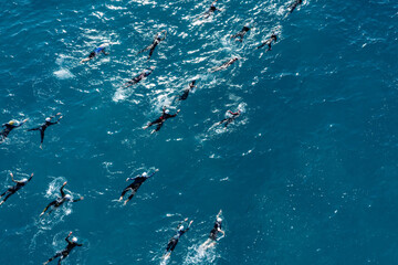 Naklejka premium Group of athletes swimming in ocean during triathlon competition