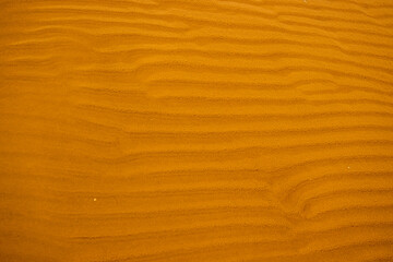 Seamless wet sand with sea water on a whole background. Empty wavy sandy sea bottom. Exotic Sandy Ocean beach surface. Top view. Simple, minimalistic photo. Ideal concept for banner, poster, ads.