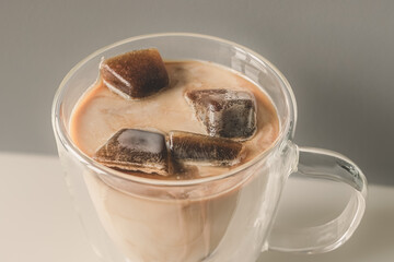 Frozen coffee cubes filled with milk in a glass cup. Cool coffee drink. Quench your thirst. Rescue from abnormal heat. Morning drink. Coffee break. Coffee cocktail. Summer menu.