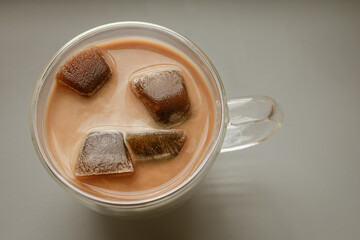 Frozen coffee cubes filled with milk in a glass cup. Cool coffee drink. Quench your thirst. Rescue from abnormal heat. Morning drink. Coffee break. Coffee cocktail. Summer menu.