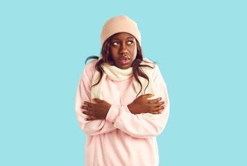Portrait of unhappy African American woman who is freezing because of cold weather and can't keep...
