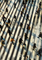 Obraz premium In the center of the picture is an overhead view of people crossing in motion, with blurred figures and motion blur. The background color has black and white stripes on it. 
