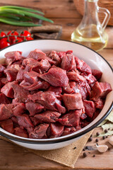 Raw sliced beef or lamb meat, spices, herbs on a wooden background. Goulash. Raw organic meat.