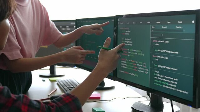 Slow motion back end software developer engineer for computer programming working together on debugging writing computing code, solving complex algorithms display on monitor in office. Burgeoning