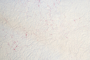 Crinkled, textured, vintage paper background with hints of red.