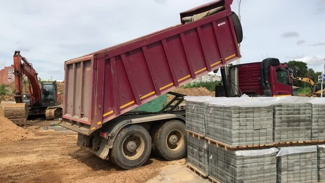 dump truck unloads sand at a construction site