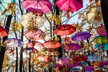 Many open umbrellas hanging above the head in city park © ihorbondarenko