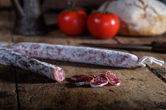 Traditional cured meats on rustic wooden table with fresh tomatoes