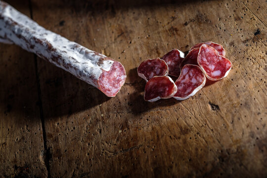 Sliced cured sausage and fuet on rustic wooden background