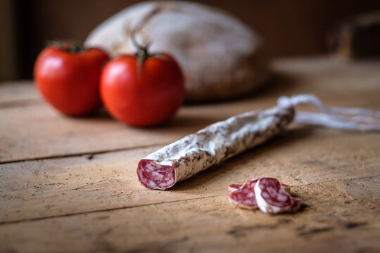 Cured sausage and fresh tomatoes on rustic wooden table
