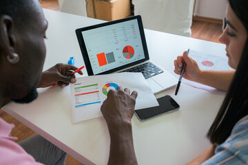 Colleagues analyzing financial data on laptop and documents
