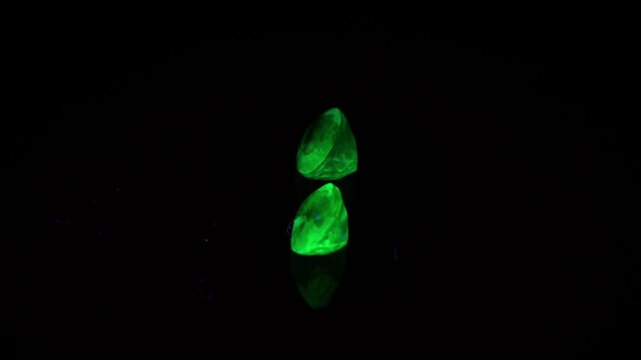 natural green opal hyalite under uv light on the black background