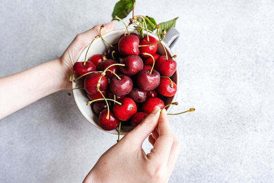 Anonymous cropped peron hands holding a bowl with fresh red cherries