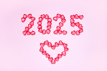 New Year 2025 inscription from glass hearts on a pink background. Pantone color 2025. Idea and...