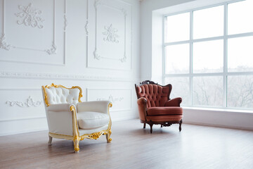 Vintage armchairs in a stylish white room with a large window