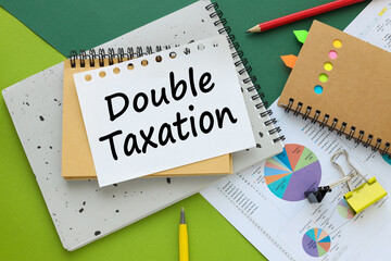 DOUBLE TAXATION, business concept. green background and notepads on financial blocks. text on page