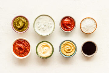 Set of sauces in bowls - pesto salsa mustard and others. Food background
