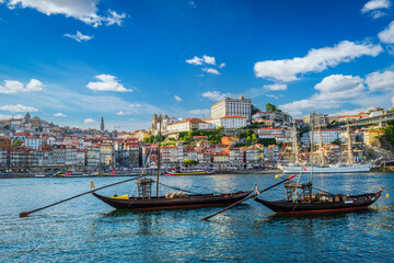 Fototapeta premium View of Porto city and Douro river with traditional boats with port wine barrels and sailing ship from famous tourist viewpoint Marginal de Gaia riverfront. Porto, Vila Nova de Gaia, Portugal