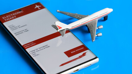 Electronic air ticket form on the screen of a mobile phone next to a toy passenger plane. Concept of buying online and using an electronic airline ticket for travel. Photo