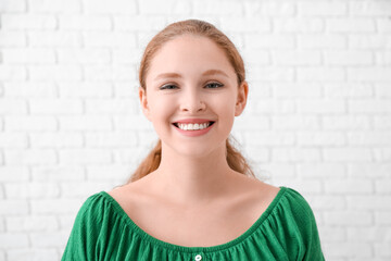 Portrait of happy redhead woman near white brick wall