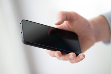 male hand holding smartphone close up, man using mobile phone