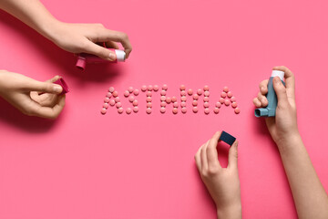 Child's hands with inhalers and word ASTHMA made of pills on pink background