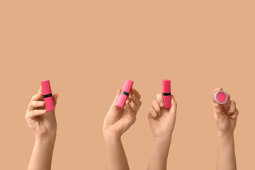 Female hands with lipsticks on beige background