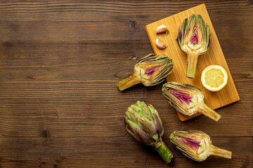 Green artichokes heads with ingredients garlic and lemon. Cooking background