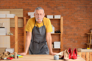 Portrait of mature shoemaker at table in workshop