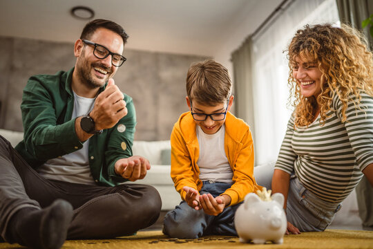 mam dad and son sit on the carpet and save money in the piggy bank