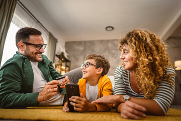 Mum,dad and son have online shopping on mobile phone with credit card