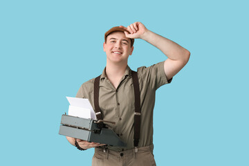 Happy young man with vintage typewriter on blue background