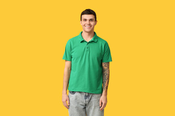 Fototapeta premium Handsome young man in stylish green t-shirt on yellow background