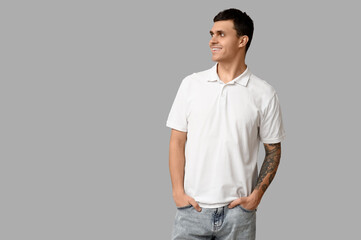 Fototapeta premium Handsome young man in stylish white t-shirt on grey background
