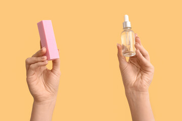 Female hands with bottle of cuticle oil and buffer on yellow background