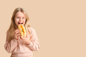 Cute little girl eating tasty hot dog on color background