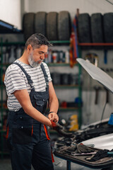 Auto mechanic at repair shop preparing for work and putting gloves on.