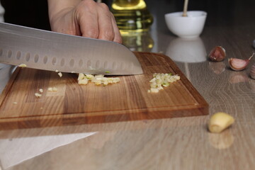 A girl cuts garlic from a side angle. Dishes with the addition of garlic, spicy cuisine