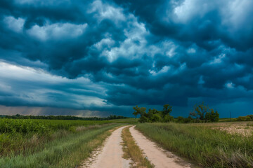 Fototapeta premium Dirt road with dark storm clouds