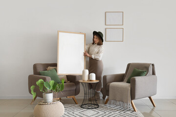 Young woman with big blank frame at home