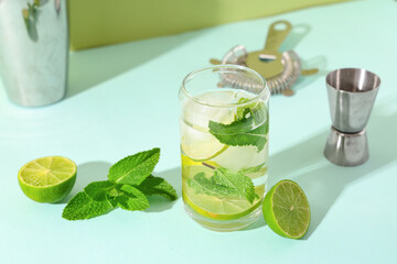 Glass of fresh mojito with cocktail jigger on blue background