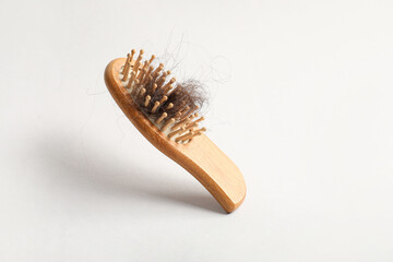 Brush with clump of hair on light background. Hair loss problem
