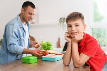 Little boy with his father packing school lunchbox in kitchen