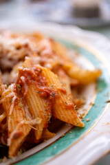 penne pasta with cheese and tomatoes on vintage plate in close-up
