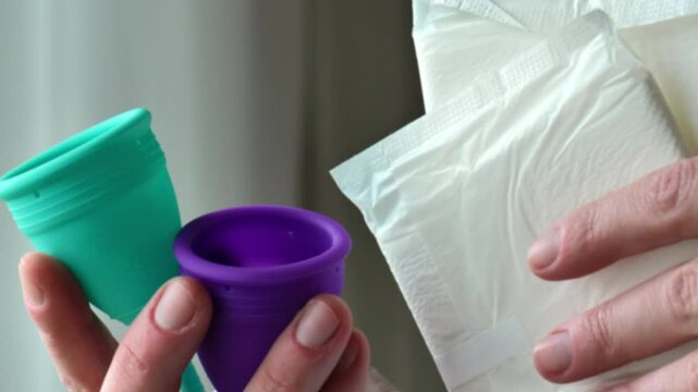 Menstrual cup and sanitary pads. Choosing a hygiene product.Womens periods.reusable silicone menstrual cup.Silicone mestrual cups in hands close-up. Zero vaste and reasonable hygiene and consumption